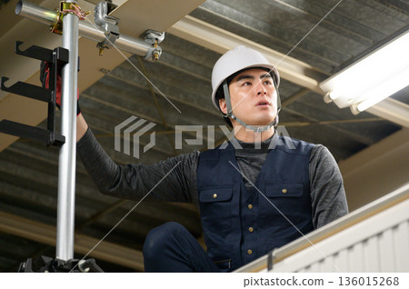 A man working wearing a helmet 136015268