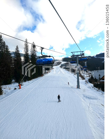 Ski slope with skiers and snowboarders on the slope 136015458