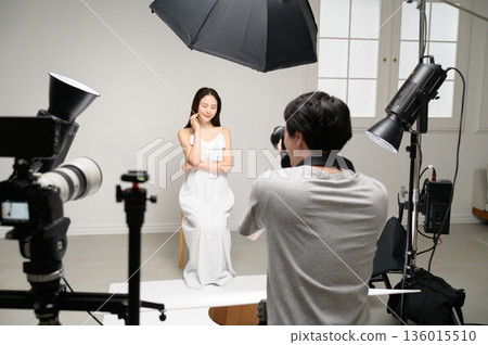 Male photographer photographing a female model in a studio 136015510