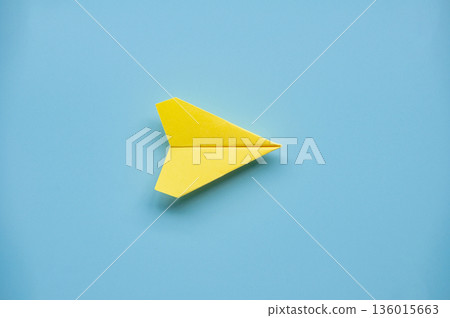 Single yellow paper airplane on blue background emphasizing individuality bold ideas and standout thinking. 136015663