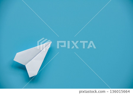 White paper airplane isolated on blue background symbolizing simplicity direction and creative freedom concept White paper airplane isolated on blue background symbolizing simplicity direction and creative freedom concept 136015664