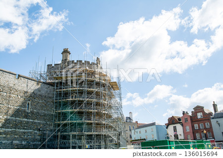 Historic stone Windsor Castle with scaffolding erected for construction under a bright blue sky and floating clouds. A streetscape on the outskirts of London Historic stone Windsor Castle with scaffolding erected for construction under a bright blue sky and floating clouds. A streetscape on the outskirts of London 136015694