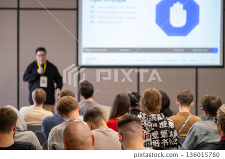 Speaker presents to audience in conference room with large screen projection 136015780