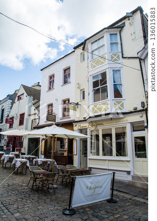 在倫敦郊區溫莎一條鵝卵石街道上，商店前擺放著桌椅。 136015883