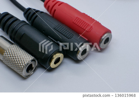 Close-up of audio jack adapters and connectors on a clean white background. Sound accessories for headphones, microphones, music devices, recording, and audio equipment 136015968