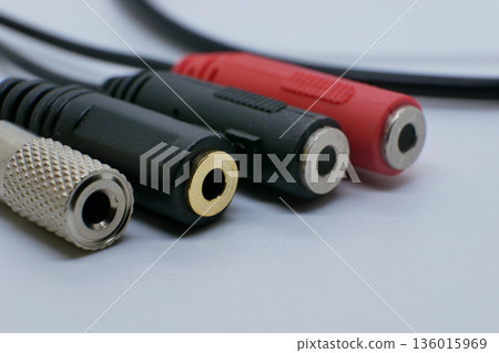 Close-up of audio jack adapters and connectors on a clean white background. Sound accessories for headphones, microphones, music devices, recording, and audio equipment 136015969