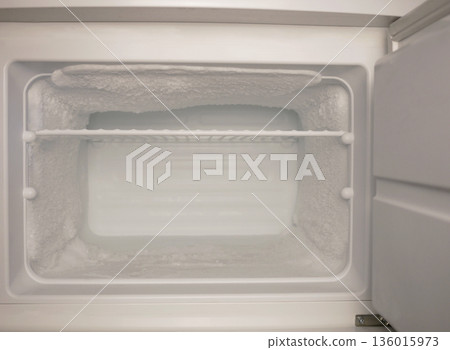 Empty freezer with heavy frost and ice buildup. Cold storage concept, refrigeration problem, defrost need, appliance maintenance, food safety, copy space 136015973
