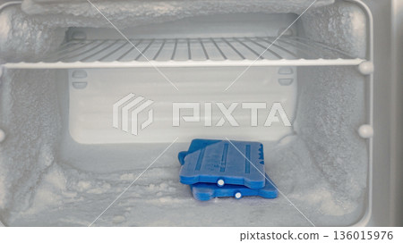 Frosted Freezer Interior with Ice Packs and Heavy Ice Buildup 136015976