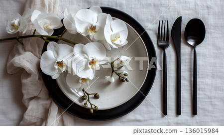 Elegant table setting with black utensils and white orchids on soft fabric 136015984