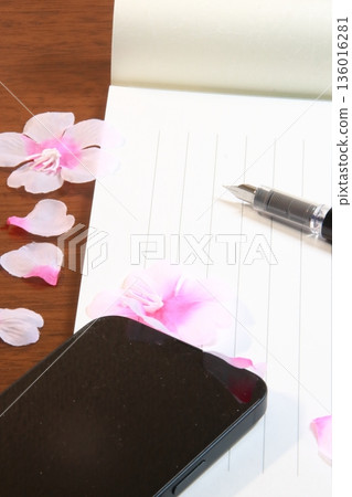 Image of spring in Japan: Letter paper, fountain pen, smartphone, and cherry blossom petals (vertical) on a desk Image of spring in Japan: Letter paper, fountain pen, smartphone, and cherry blossom petals (vertical) on a desk 136016281