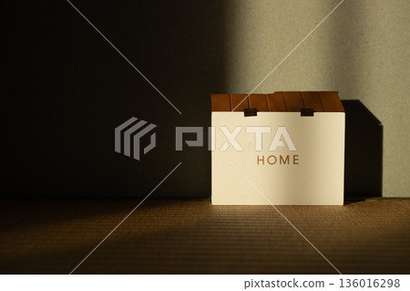 昏暗的房間裡擺放著一件寫著「家」字的裝飾品,給人一種陽光照耀著房子的感覺。 昏暗的房間裡擺放著一件寫著「家」字的裝飾品,給人一種陽光照耀著房子的感覺。 136016298