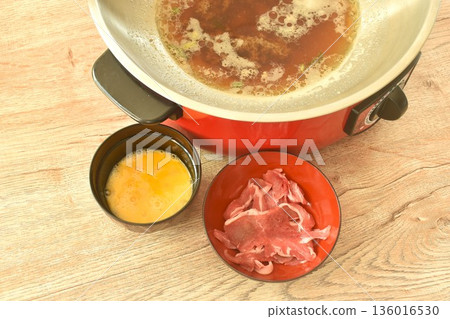 slice brisket beef and raw egg food prepare to cooking with shabu shabu soup in electric iron cooking pot on table 136016530