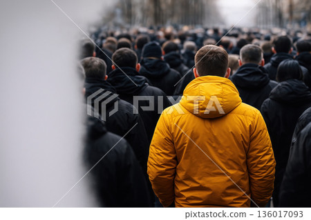A man in a bright yellow jacket among a black crowd. Space for text. A man in a bright yellow jacket among a black crowd. Space for text. 136017093