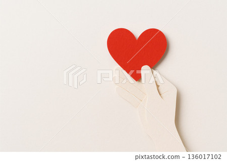 A paper hand holds a red heart, a symbol of love and care. Space for text. A paper hand holds a red heart, a symbol of love and care. Space for text. 136017102