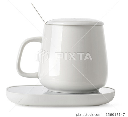 White ceramic mug set on electric warmer keeping drink hot 136017147