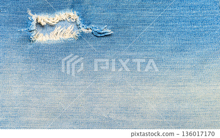 Distressed blue denim fabric texture with ripped hole 136017170