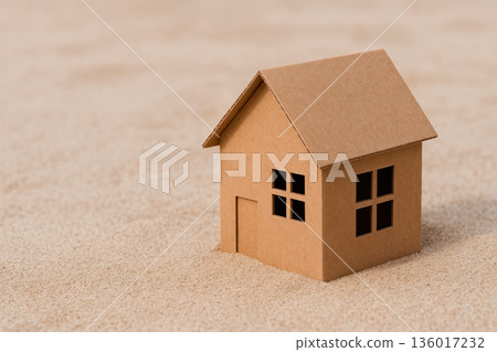 A cardboard house stands on the desert sand. Space for text. A cardboard house stands on the desert sand. Space for text. 136017232