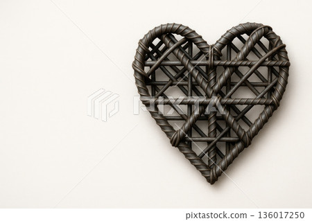 Woven metal heart on a light background. Space for text. Woven metal heart on a light background. Space for text. 136017250