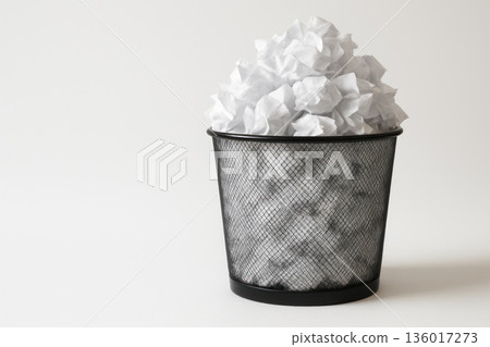 An overflowing basket of crumpled sheets of paper. Space for text. 136017273