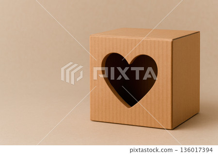 Cardboard box with a heart cut out on a beige background. Space for text. 136017394