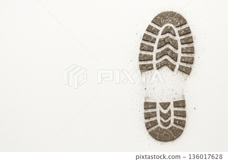 A shoe footprint made of sand on a light background. Space for text. 136017628