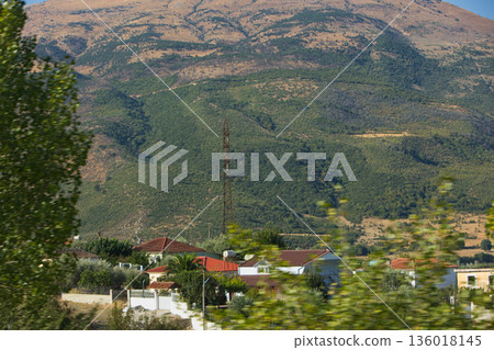 Hillside village landscape captured from the road in August 2025, showing traditional houses scattered across dry Mediterranean mountains under a calm summer sky. Hillside village landscape captured from the road in August 2025, showing traditional houses scattered across dry Mediterranean mountains under a calm summer sky. 136018145