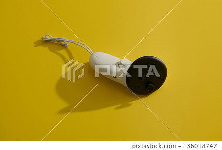 Compact White And Black Personal Massager On Bright Yellow Studio Surface 136018747