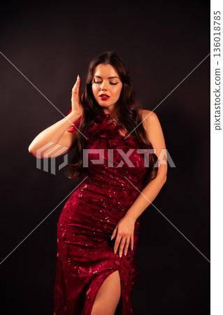 Woman in a red dress poses confidently in front of a dark background for a Valentines Day inspired scene 136018785