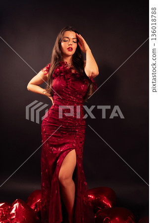Beautiful woman wearing a red dress surrounded by red hearts for Valentines Day celebration 136018788