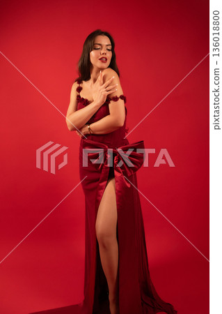 Woman in red dress posing against a red background for a Valentines Day themed shoot 136018800