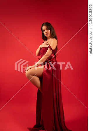 Beautiful woman in red dress posing on red background for Valentines Day celebration Beautiful woman in red dress posing on red background for Valentines Day celebration 136018806
