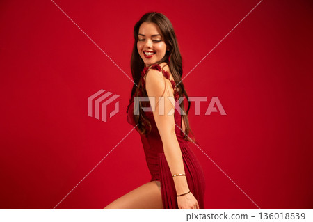 Woman in red dress smiles against red background for Valentines Day celebration while expressing joy and love Woman in red dress smiles against red background for Valentines Day celebration while expressing joy and love 136018839