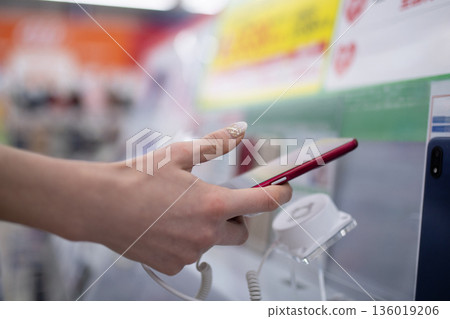 商店裡，一位女士正在挑選智慧型手機。 136019206