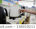A woman's hand choosing an electric kettle at a home appliance store 136019211