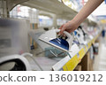 A woman's hand choosing an iron at a home appliance store 136019212