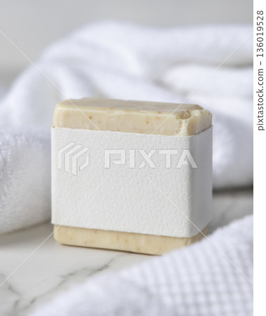 Mockup of beige solid soap bar with blank paper label near white bath towel, personal care packaging 136019528