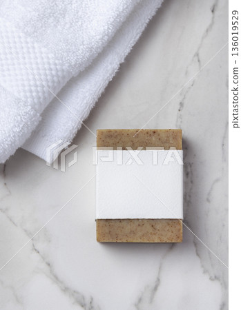 Mockup of brown solid soap bar with blank paper label near white bath towel on marble, personal care Mockup of brown solid soap bar with blank paper label near white bath towel on marble, personal care 136019529