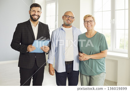 Happy real estate agent and mature couple celebrating new home purchase together 136019899