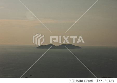 Mountain range rising above a calm blue sea under a clear sky, forming a minimalistic coastal landscape. Serene natural scenery captured on August 2025. Mountain range rising above a calm blue sea under a clear sky, forming a minimalistic coastal landscape. Serene natural scenery captured on August 2025. 136020485