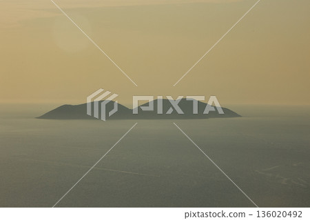 Mountain range rising above a calm blue sea under a clear sky, forming a minimalistic coastal landscape. Serene natural scenery captured on August 2025. Mountain range rising above a calm blue sea under a clear sky, forming a minimalistic coastal landscape. Serene natural scenery captured on August 2025. 136020492