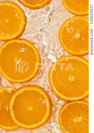 Fresh slices of oranges into water, splash water top view. 136020857