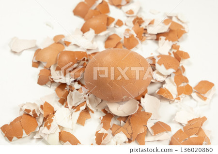 Unpeeled boiled egg with cracked shell on the background of eggshells Unpeeled boiled egg with cracked shell on the background of eggshells 136020860