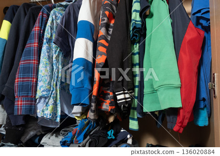 Organization of space in the wardrobe for childrens clothes, hanging sweaters on hangers in a wooden wardrobe Organization of space in the wardrobe for childrens clothes, hanging sweaters on hangers in a wooden wardrobe 136020884