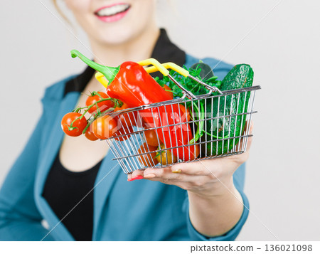 Woman holds shopping basket with vegetables 136021098