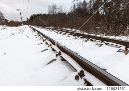 Winter landscape featuring snow-covered railway tracks extend toward the horizon 136021861