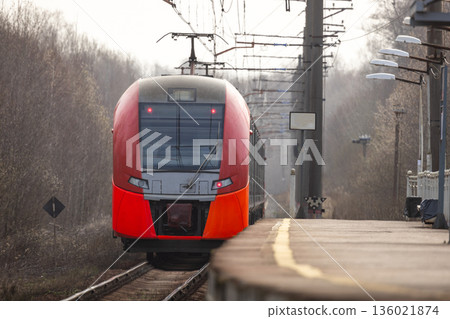 A sleek red modern train pulls into a quiet platform A sleek red modern train pulls into a quiet platform 136021874