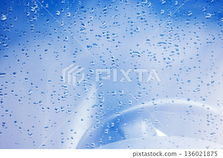 Close-up of droplets on a car glass reflecting a blue sky Close-up of droplets on a car glass reflecting a blue sky 136021875