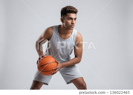 Young Indian man in defensive stance with basketball ready for play Young Indian man in defensive stance with basketball ready for play 136022465