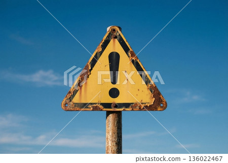 Yellow triangular warning sign with exclamation mark against sky 136022467