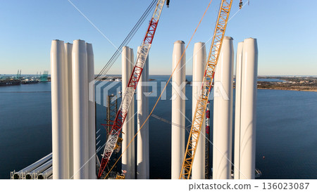 Aerial view of wind turbine tower sections with cranes at port Aerial view of wind turbine tower sections with cranes at port 136023087